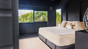 Een slaapkamer met een bed, een raam en uitzicht op groen.