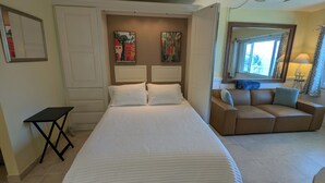 Ein Schlafzimmer mit einem Bett, einem kleinen Tisch, einer Couch und zwei an der Wand hängenden Bildern.