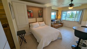 Ein Schlafzimmer mit einem Bett, einem kleinen Tisch, einem Stuhl und einem Fenster mit Meerblick.