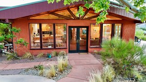A modern house with a large glass door and windows, surrounded by a landscaped garden with various plants and a patio area.