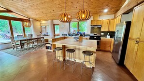 A spacious kitchen with a central island, wooden cabinets, and a stainless steel refrigerator.