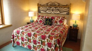 A bed with a floral bedspread, two bedside lamps, and a peace symbol pillow.
