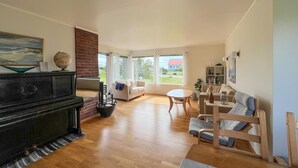 A spacious living room with a fireplace, a sofa, a coffee table, and a piano.