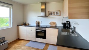 A compact kitchen with a black countertop, stainless steel sink, and a built-in oven. There is a window providing a view of the outdoors.