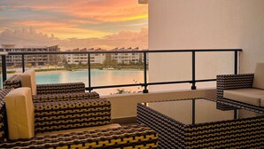 Un balcon avec des sièges d’extérieur et une vue sur une piscine et des bâtiments.