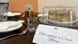 A dining table set with a cake, a pitcher of tea, and a menu titled "Bem vindos a Casa Maru". - MHV Milagres - Casa Naru (Passo de Camaragibe)