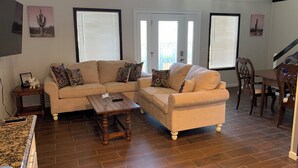 A living room with a beige sectional sofa, a wooden coffee table, and a dining area with a wooden table and chairs. - Lovely 3-bedroom house with loft in Burlington (Burlington)