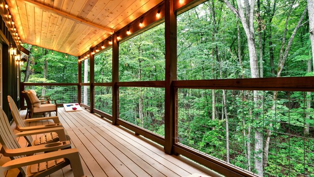 Una terraza de madera con sillas y una mesa, con vista a un bosque.