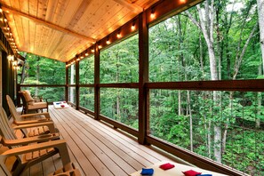 Una terraza de madera con sillas y una mesa, con vista a un bosque.