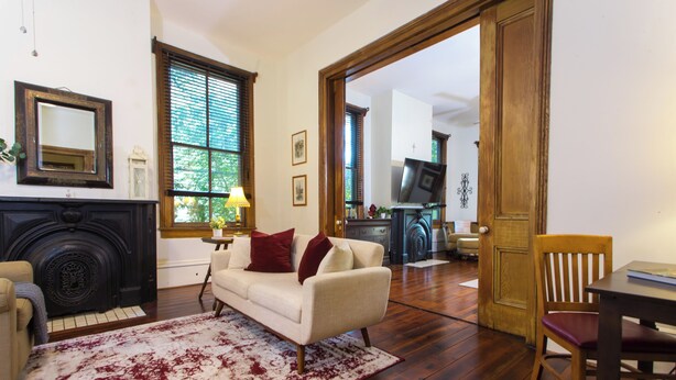 A living room with a fireplace, a sofa, a coffee table, and a dining table. - Historic Downtown Loft A (Pensacola)