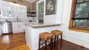A kitchen with white cabinets, a stainless steel dishwasher, and a wooden floor. - Historic Downtown Loft A (Pensacola)
