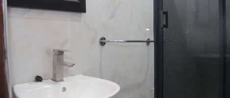A bathroom with a white sink, a mirror, and a glass shower enclosure.