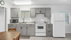A kitchen with white cabinets, a microwave, a stove, and a refrigerator. - Walk To Beach, North End Restaurants, Night Life Steps Away! (Fort Myers Beach)