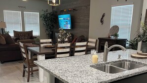 A modern kitchen with a granite countertop, dark cabinetry, and a built-in sink. - Saguaro Bloom Beauty (Marana)