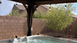 A hot tub with a wooden deck, a brick wall, and a tree in the background. - Saguaro Bloom Beauty (Marana)