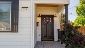 Una casa con una porta d'ingresso scura, una cassetta delle lettere e il numero '615' sulla parete.