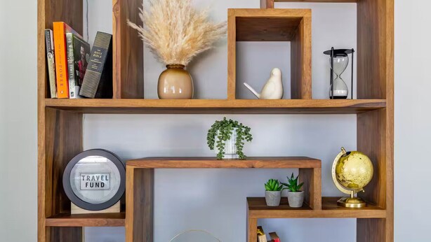 A wooden bookshelf with various items including books, a globe, a clock, and decorative plants. - Downtown Charm Meets Waterfront Walk to Everything (Vancouver)