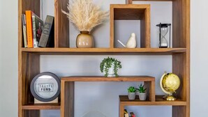 Una libreria in legno con diversi oggetti, tra cui libri, un globo, una sveglia e piante ornamentali.