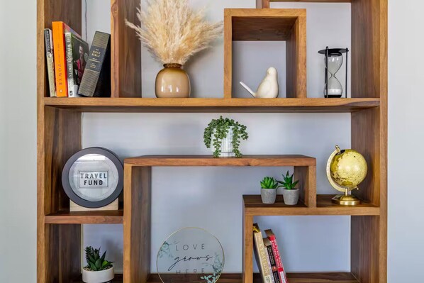 A wooden bookshelf with various items including books, a globe, a clock, and decorative plants. - Downtown Charm Meets Waterfront Walk to Everything (Vancouver)