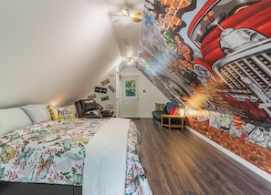 Une chambre à coucher avec un lit, une chaise, une fresque murale et un ventilateur de plafond.