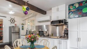 A modern kitchen with white cabinets, a central island with a vase of flowers, and a ceiling fan.