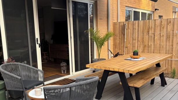 An outdoor patio with a wooden table and chairs, a small round table with a cushion, and a potted plant. - Luxury with a 2 min walk to beach! A new way to Rosebud (Rosebud)