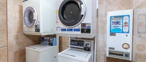 A laundry facility with two front-loading washing machines and a coin-operated dryer.