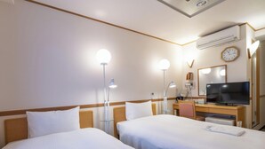Hotellihuone, jossa on kaksi sänkyä, työpöytä, jossa on televisio, peili ja seinäkello.