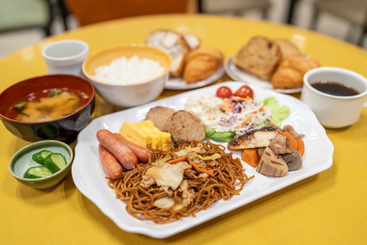 A table with a variety of dishes including noodles, vegetables, and meat.