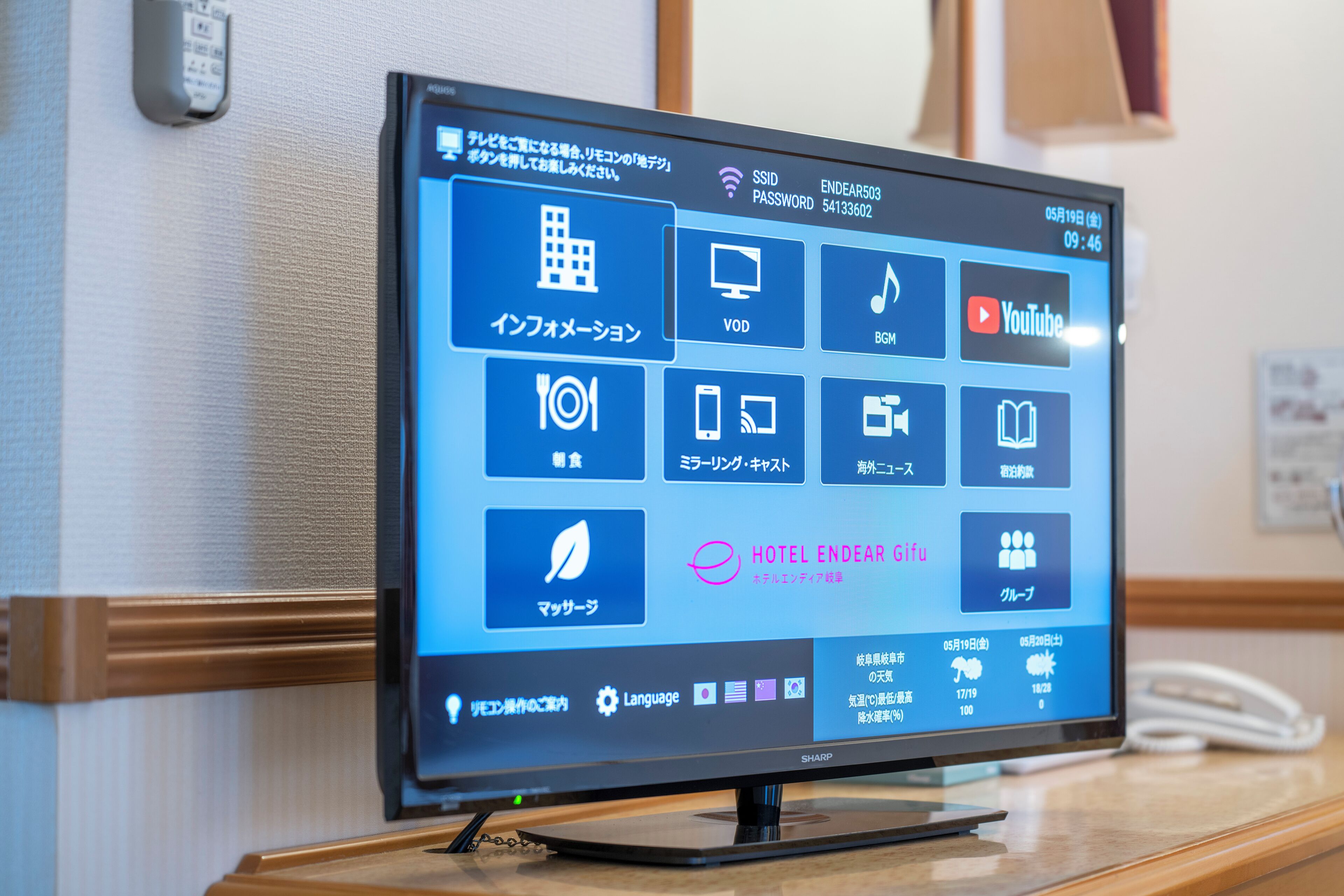 A hotel room's digital interface with various service icons, including a clock, a calendar, and a weather widget.