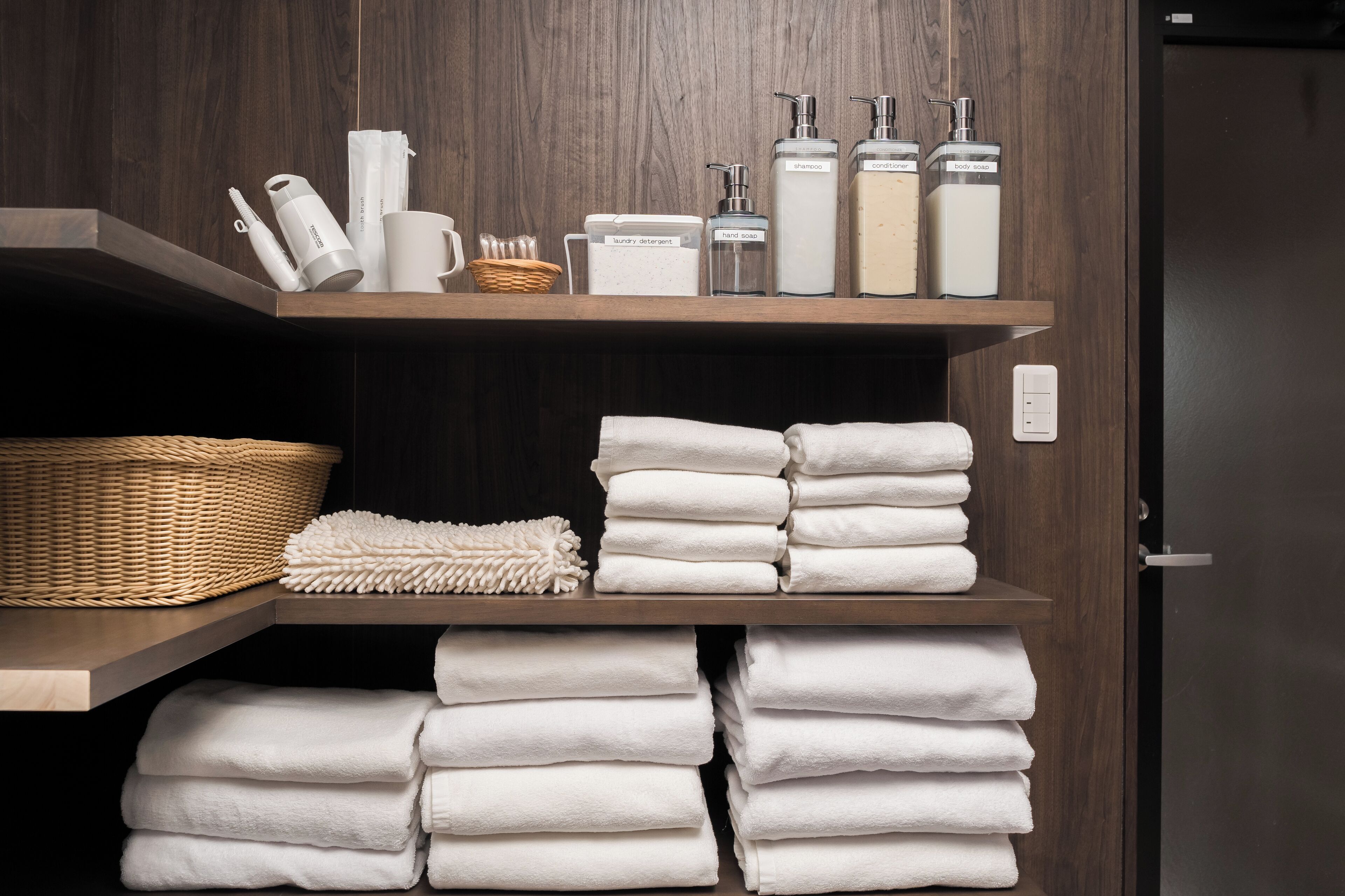 A bathroom with shelves holding toiletries, a basket, and neatly stacked towels.