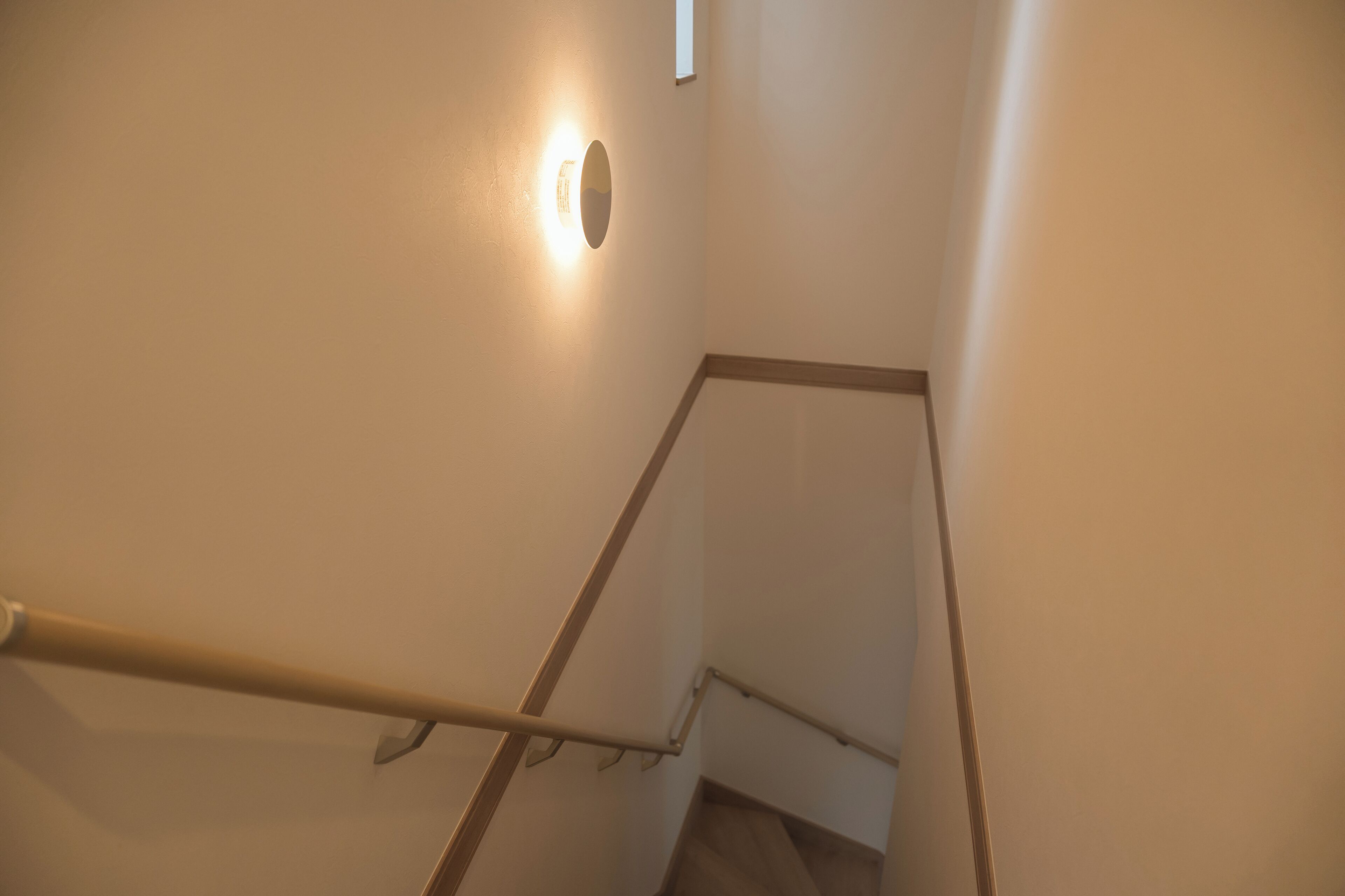 A staircase with a handrail and a light fixture on the wall.