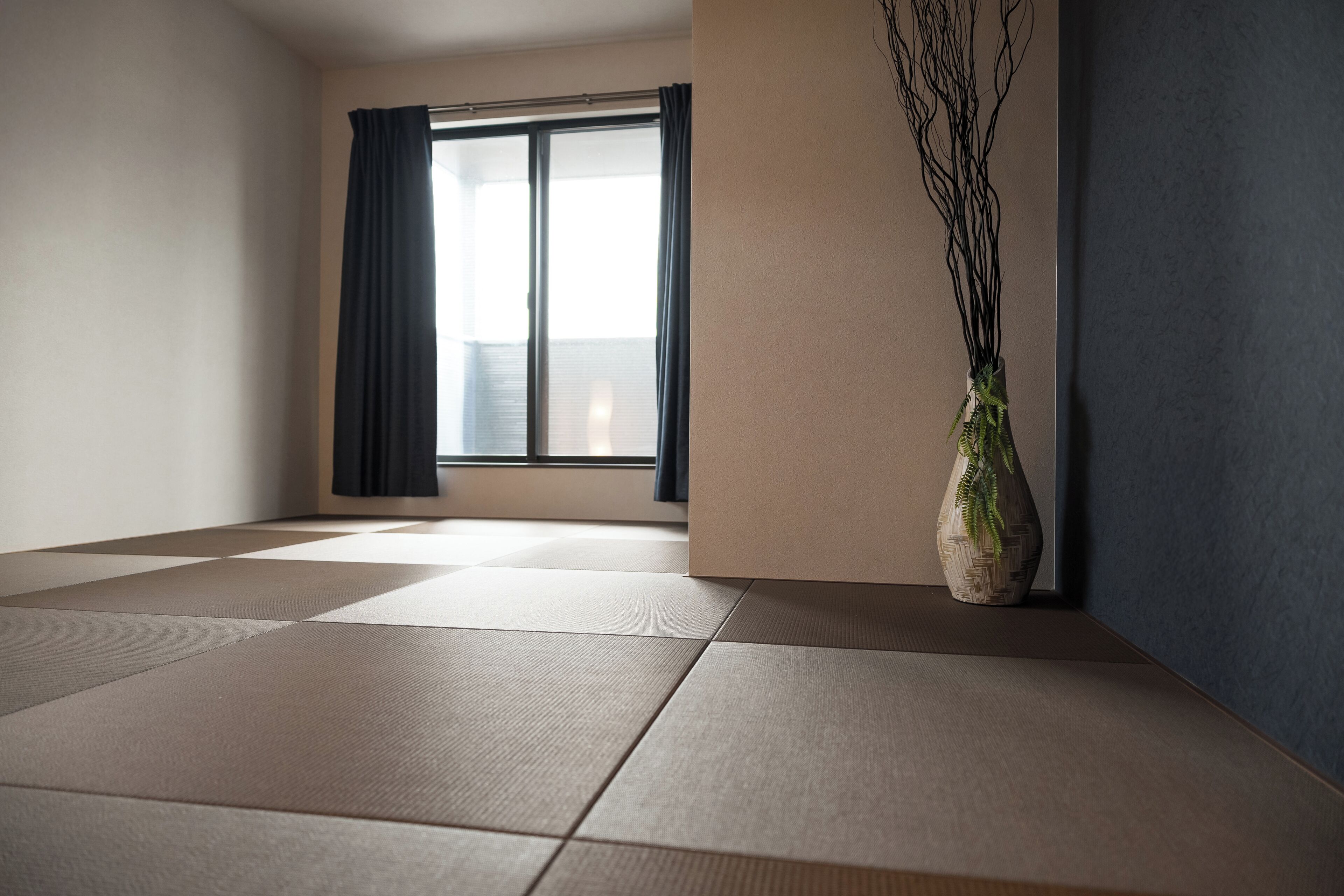 A room with tatami mats, a sliding glass door, and a vase with branches.