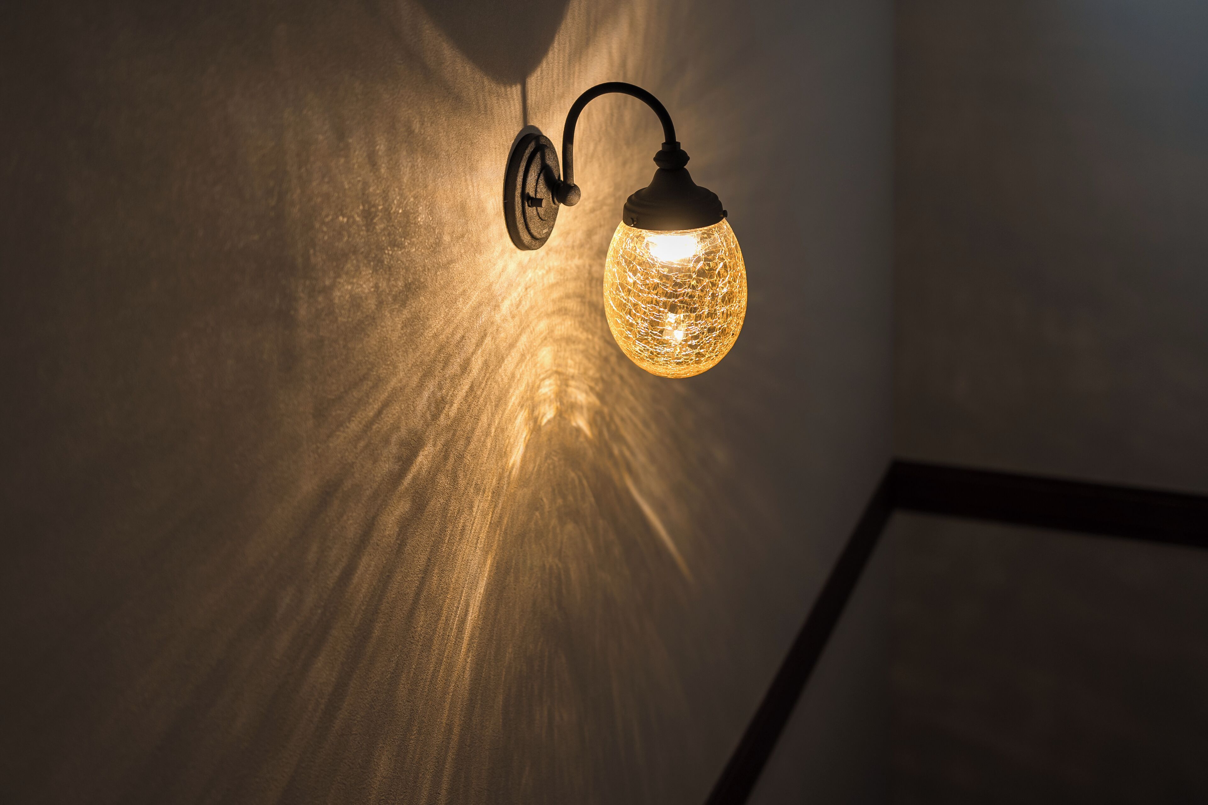 Un luminaire mural doté d’un abat-jour en verre sphérique.