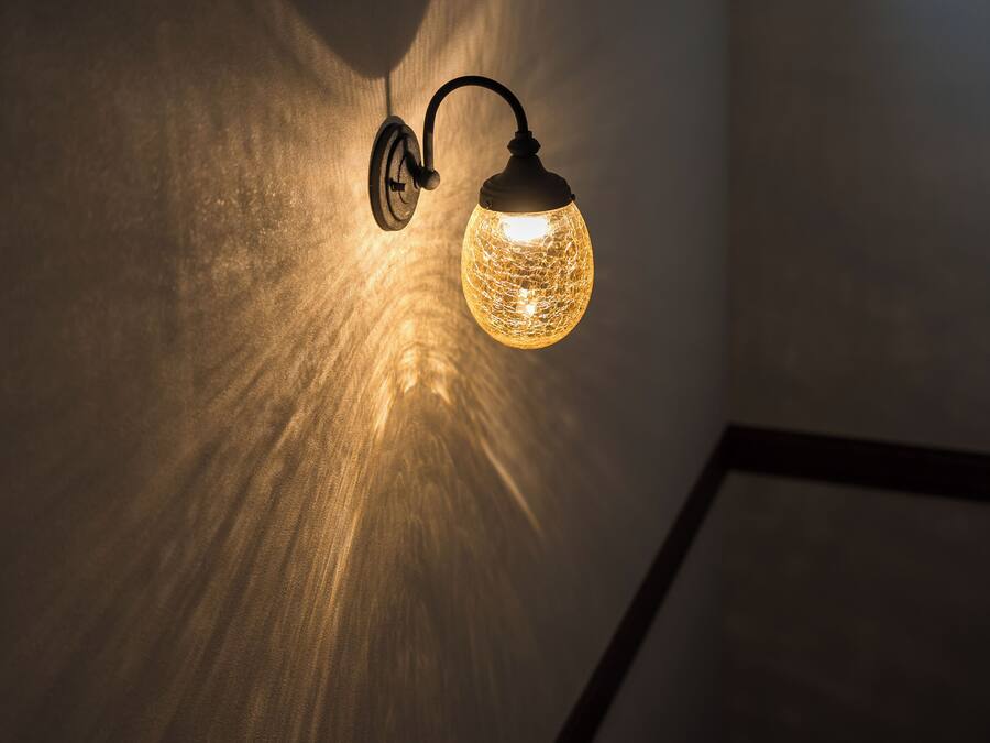 Un luminaire mural doté d’un abat-jour en verre sphérique.