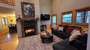 A cozy living room with a fireplace, a television, and a large window.