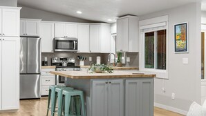 A modern kitchen with white cabinets, stainless steel appliances, and a wooden island. - House+ADU+GameRoom+Jacuzzi+Pool+Fire pit+Loft (Sisters)