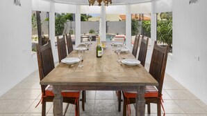 A dining area with a large wooden table, chairs, and a chandelier.