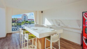 A modern kitchen with a central island, bar stools, and a view of a cityscape through large windows.