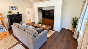 A living room with a grey sofa, wooden coffee table, and a TV.