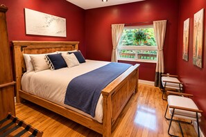 A room with a wooden bed, a window with curtains, and artwork on the walls. - Mountain Azure Shelter Cove - Lost Coast Ocean View, Sleeps 16, Retreats (Whitethorn)
