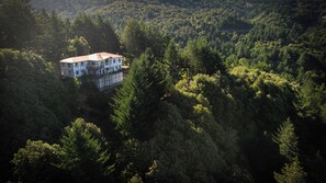 An aerial view of a large, multi-story building surrounded by dense forest. - Mountain Azure Shelter Cove - Lost Coast Ocean View, Sleeps 16, Retreats (Whitethorn)