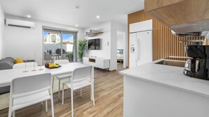 Une cuisine moderne avec des meubles blancs, une machine à café et un coin repas comprenant une table et des chaises blanches.