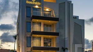 A modern hotel with a prominent 'Beachside' sign, multiple balconies, and a parking area with cars. - NEW 2BR Condo  Pool, Gym, & Steps from Palm Beach (Palm Beach)