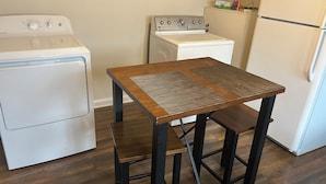 Een keuken met een houten tafel, een wasmachine, een fornuis en een koelkast.