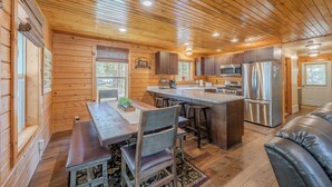 A wooden cabin interior with a kitchen, dining area, and a living space. - Yellowstone Log Cabin, Family Friendly, Fly Fishing, Trail Riding, Wi-Fi (Island Park)