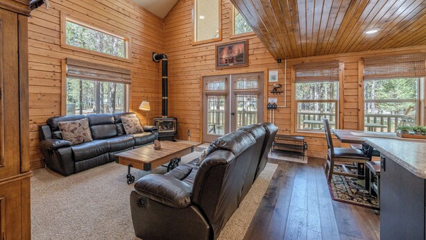 A log cabin interior with a leather sofa, dining table, and a fireplace. - Yellowstone Log Cabin, Family Friendly, Fly Fishing, Trail Riding, Wi-Fi (Island Park)