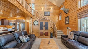 A log cabin interior with a living room, kitchen, and staircase. - Yellowstone Log Cabin, Family Friendly, Fly Fishing, Trail Riding, Wi-Fi (Island Park)