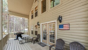 A wooden cabin with a covered porch, a grill, and a flag. - Yellowstone Log Cabin, Family Friendly, Fly Fishing, Trail Riding, Wi-Fi (Island Park)