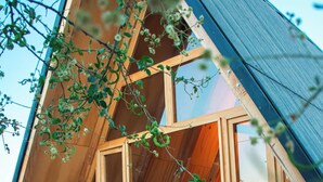 Una cabaña de madera triangular con una cama y un ventanal.
